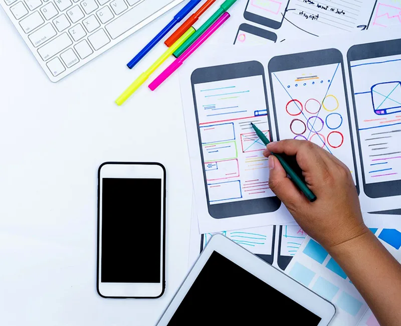 Designer sketching mobile app wireframes at a workspace desk